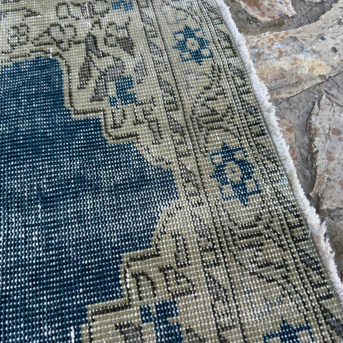 Close-up of the blue vintage turkish rug showing geometric details, hand-knotted weave, wool and cotton and low pile.