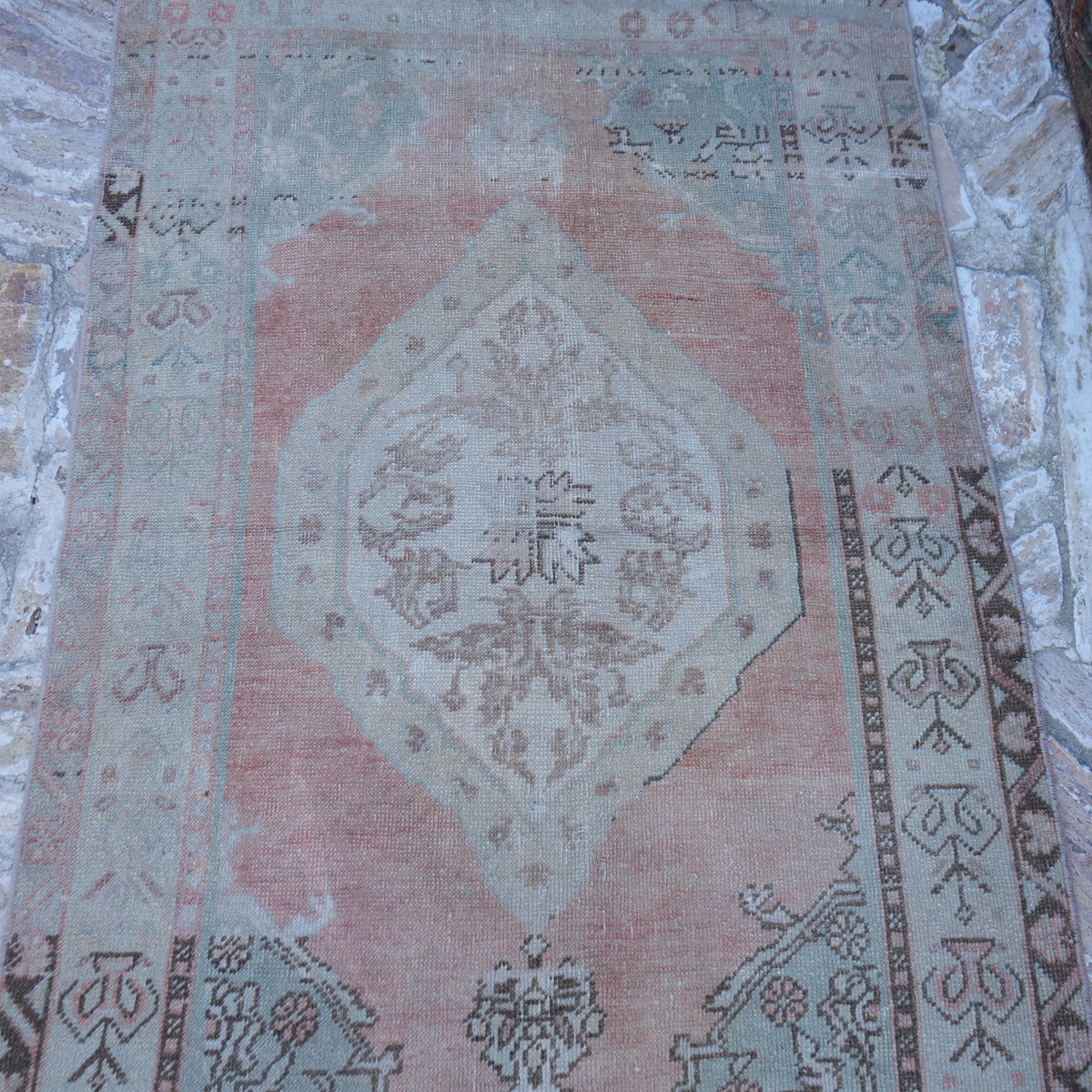 Close-up of the pink vintage turkish rug showing neutral details, hand-knotted weave, wool and low pile.