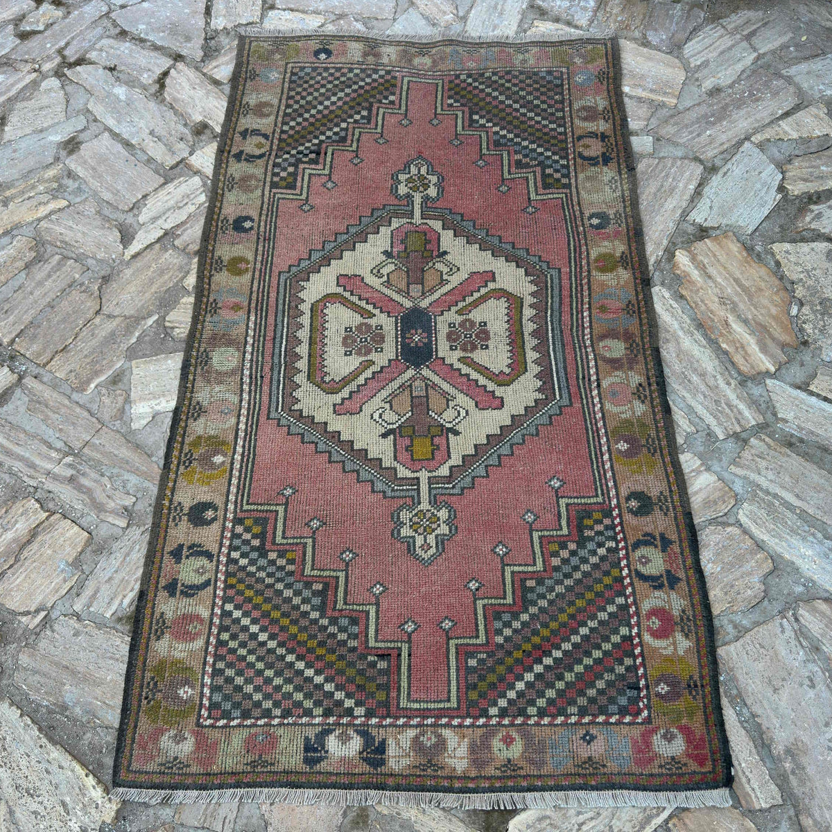 Pink 3' x 6' vintage turkish rug in wool and cotton, shown on the floor.