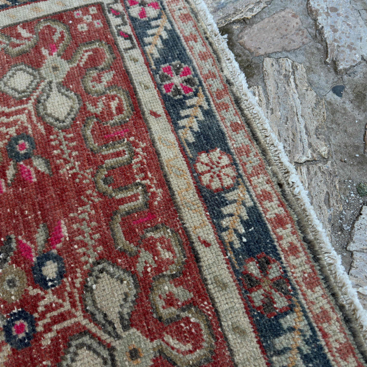 Close-up of the red vintage turkish rug showing geometric details, hand-knotted weave, wool and cotton and low pile.