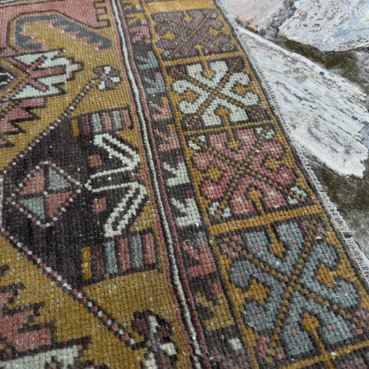 Close-up of the red vintage turkish rug showing geometric details, hand-knotted weave, wool and cotton and low pile.
