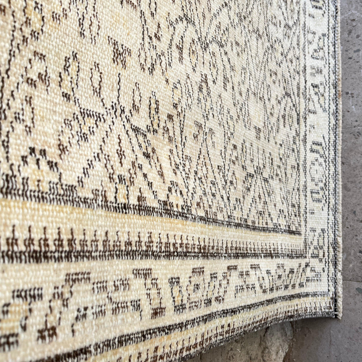 Close-up of the beige vintage turkish rug showing neutral details, hand-knotted weave, wool and cotton and low pile.
