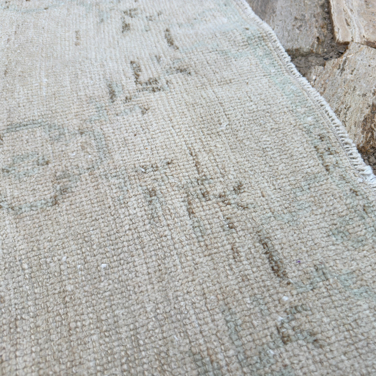 Close-up of the beige vintage turkish rug showing geometric details, hand-knotted weave, wool and cotton and low pile.