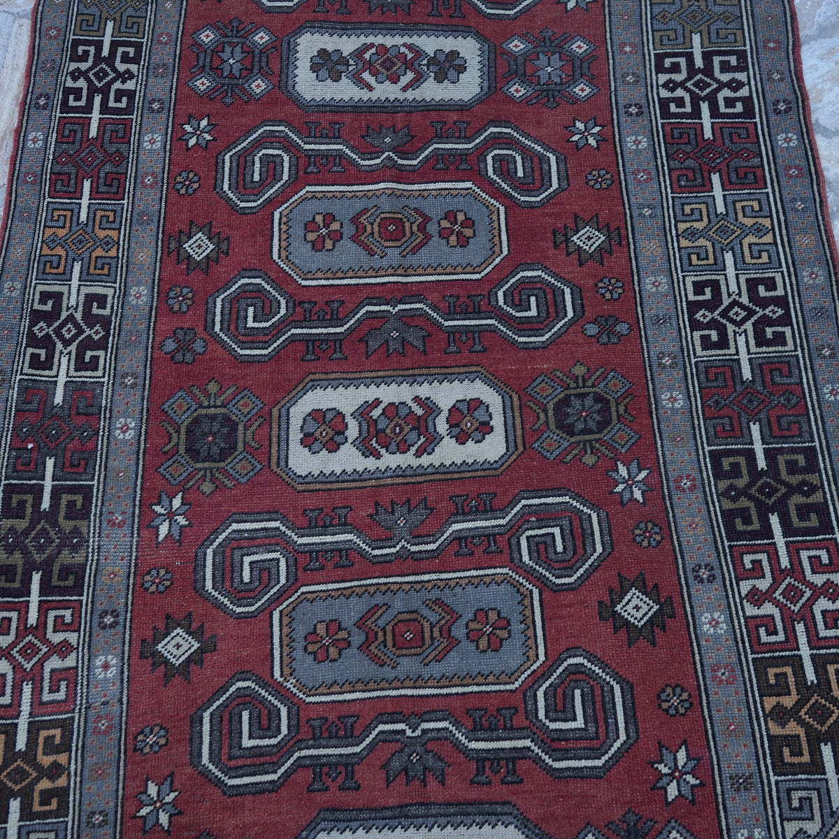 Close-up of the red vintage turkish rug showing geometric details, hand-knotted weave, wool and low pile.