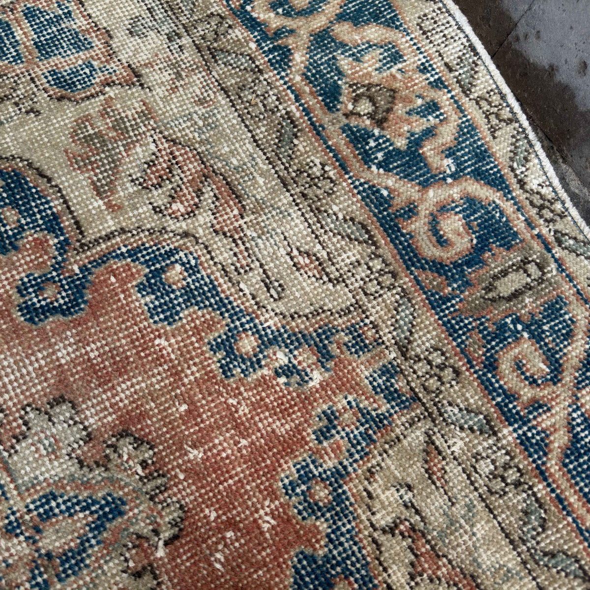 Close-up of the orange vintage turkish rug showing medallion details, hand-knotted weave, wool and cotton and low pile.