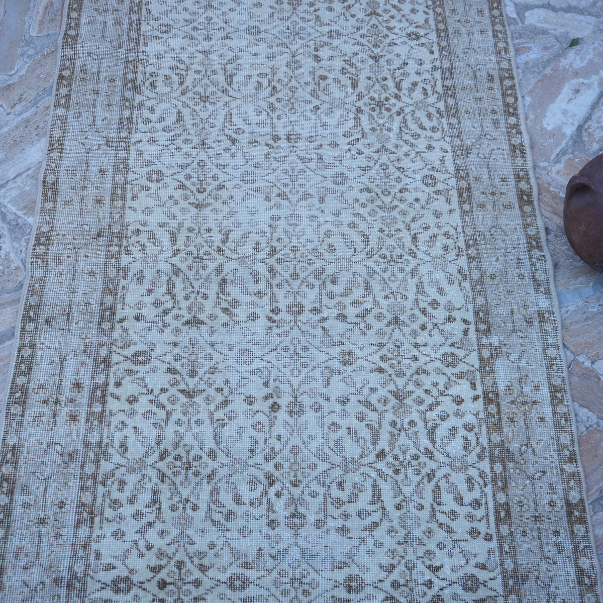 Close-up of the beige vintage turkish rug showing neutral details, hand-knotted weave, wool and cotton and low pile.