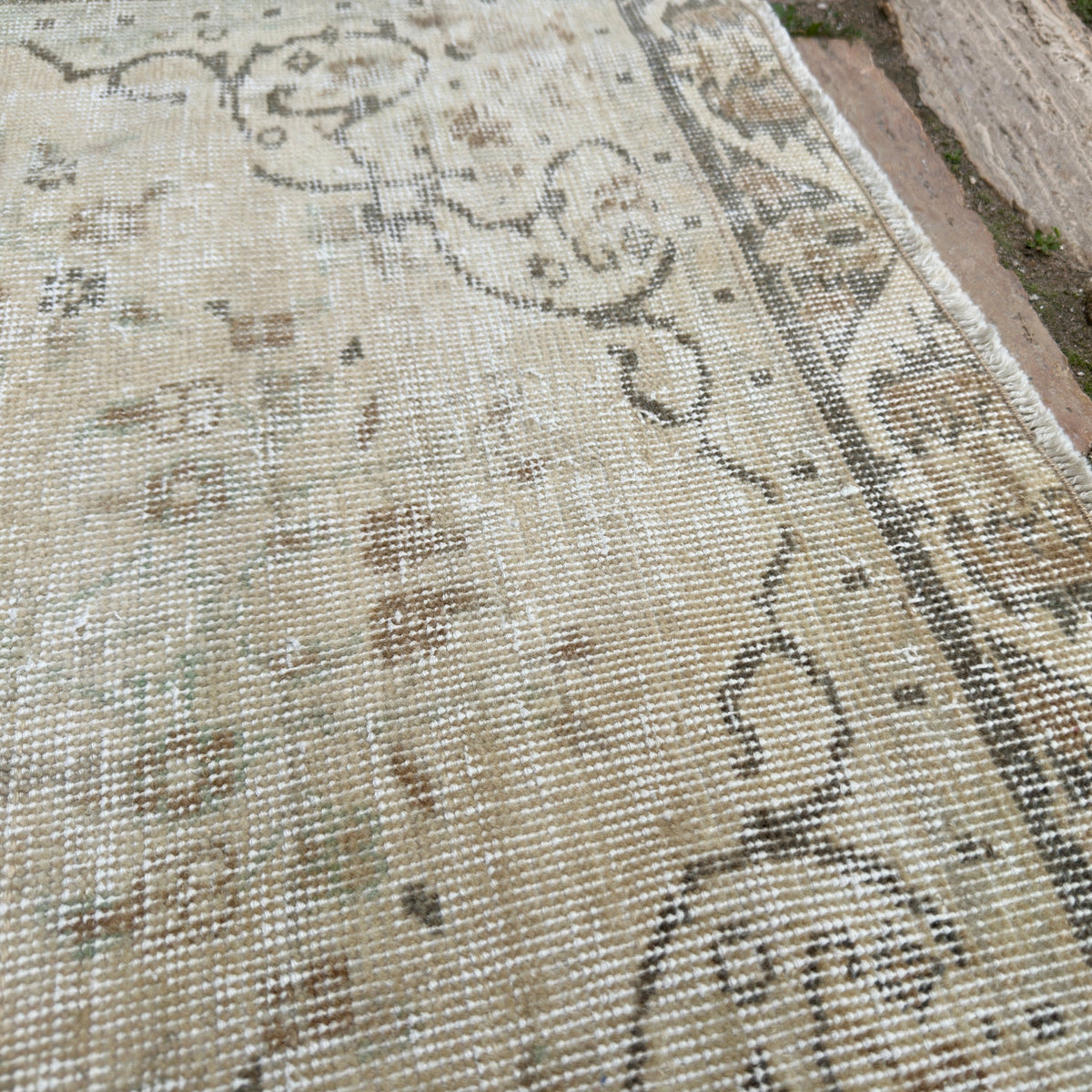 Close-up of the beige vintage turkish rug showing medallion details, hand-knotted weave, wool and cotton and low pile.