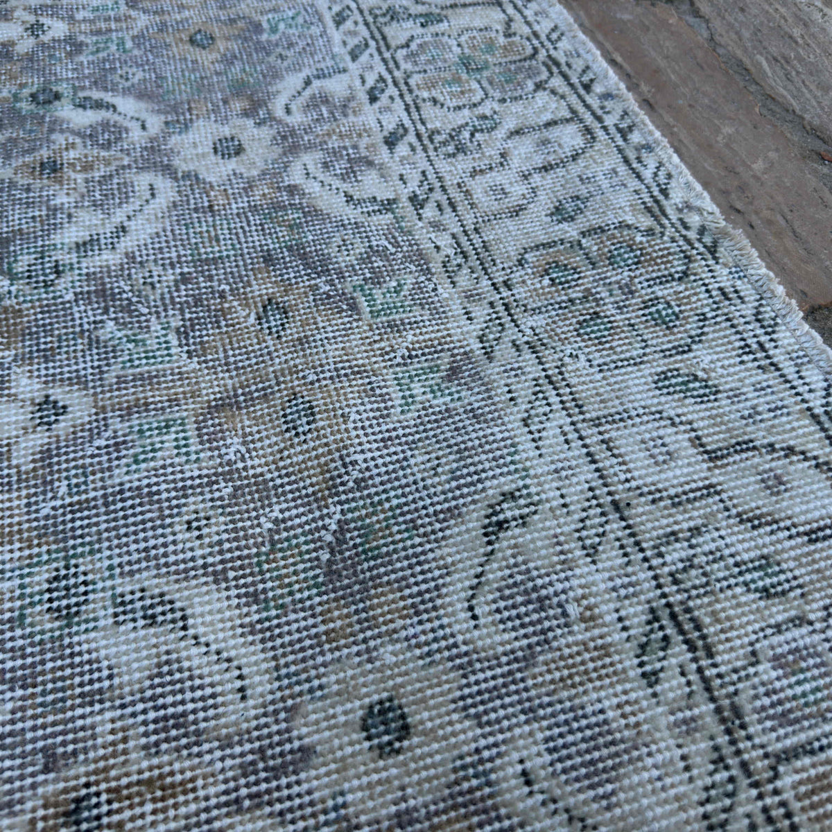 Close-up of the gray vintage turkish rug showing floral details, hand-knotted weave, wool and cotton and low pile.