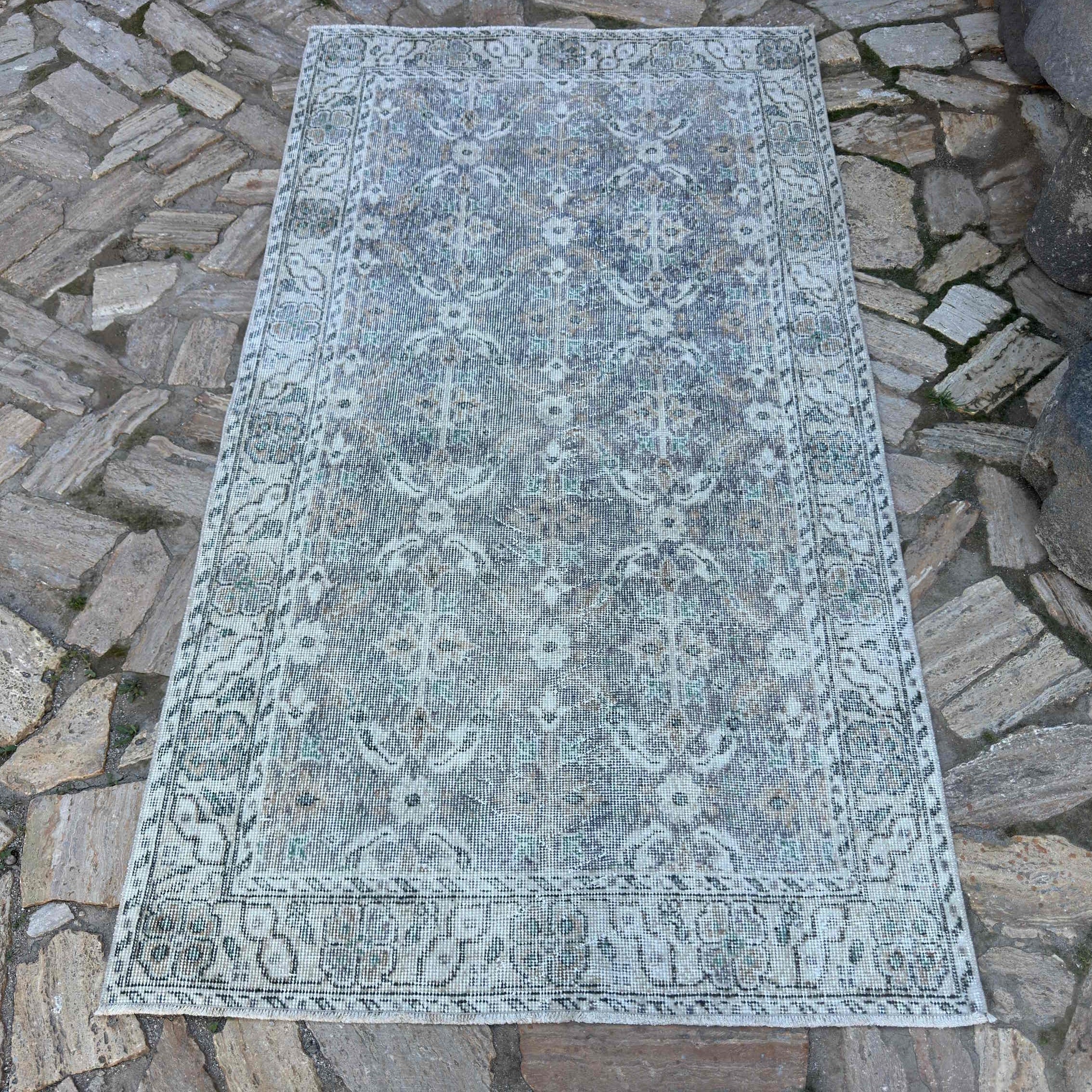 Gray 4' x 7' vintage turkish rug in wool and cotton, shown on the floor.