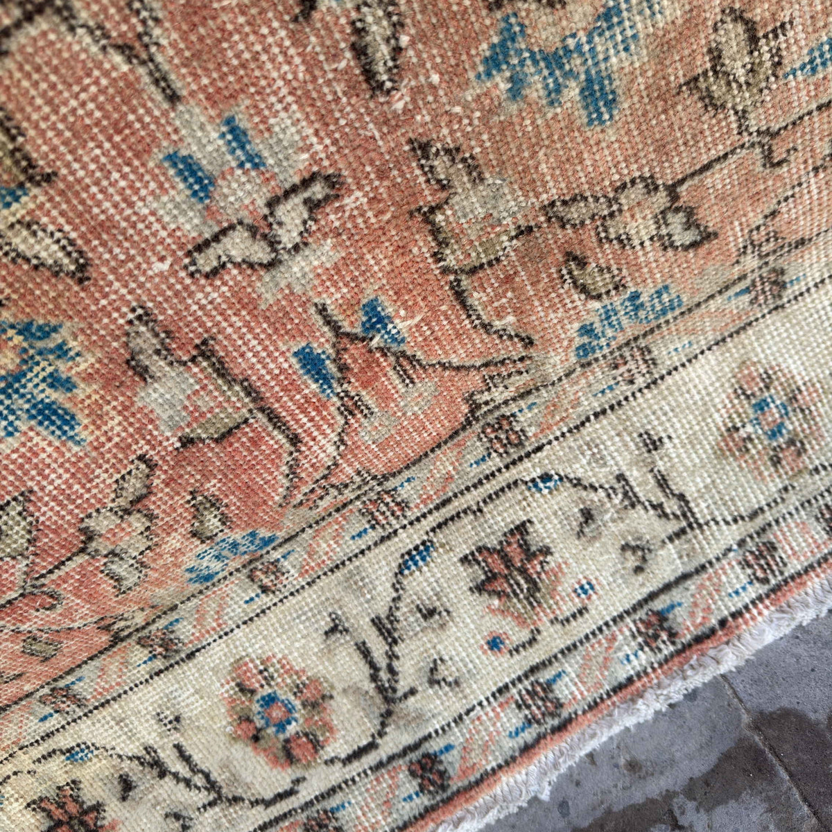 Close-up of the orange vintage turkish rug showing floral details, hand-knotted weave, wool and cotton and low pile.