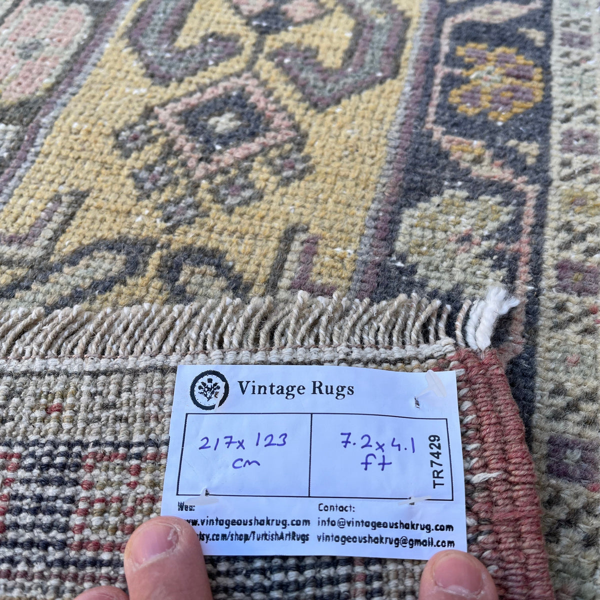 Close-up of the yellow vintage turkish rug showing geometric details, hand-knotted weave, wool and cotton and low pile.