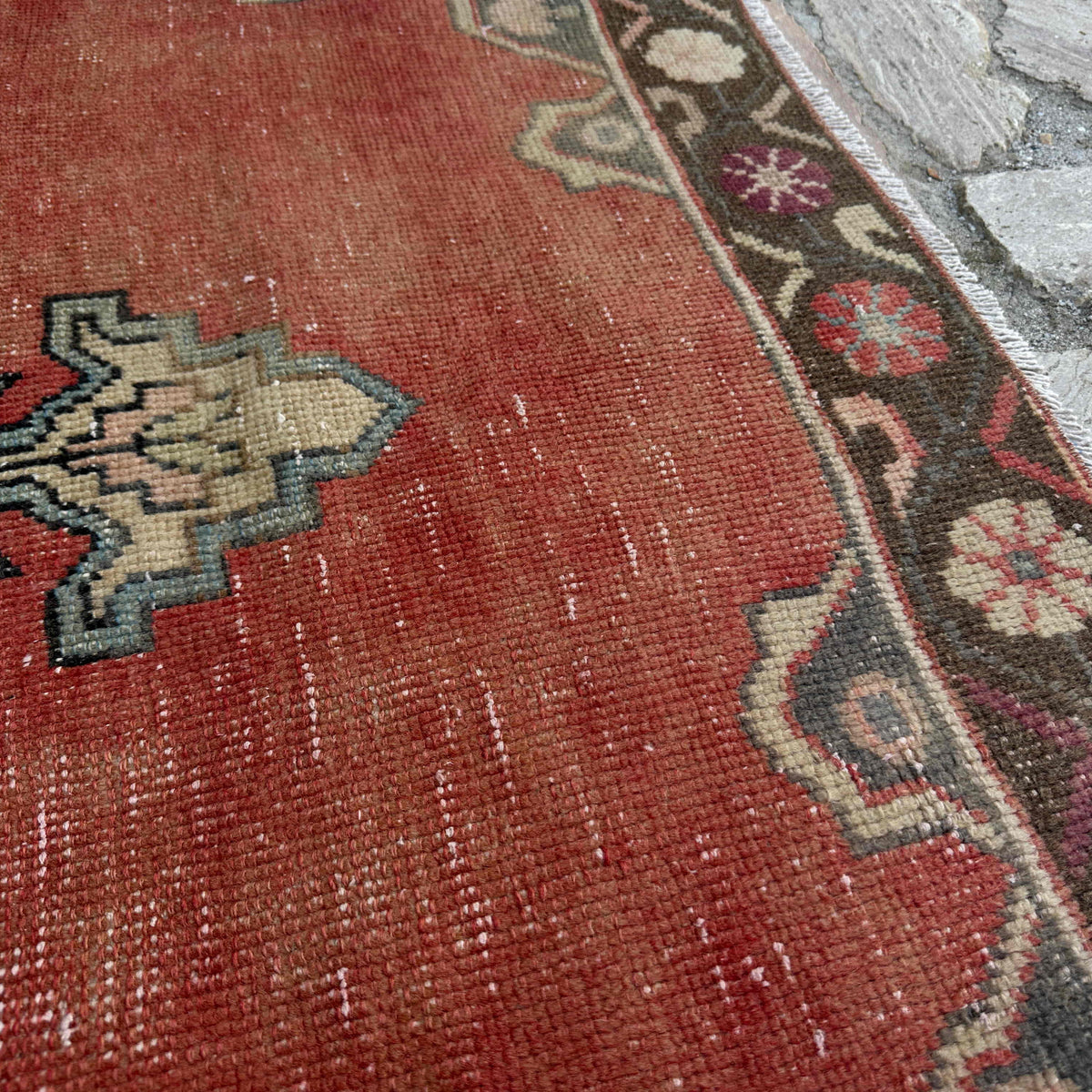 Close-up of the pale red vintage turkish rug showing medallion details, hand-knotted weave, wool and cotton and low pile.