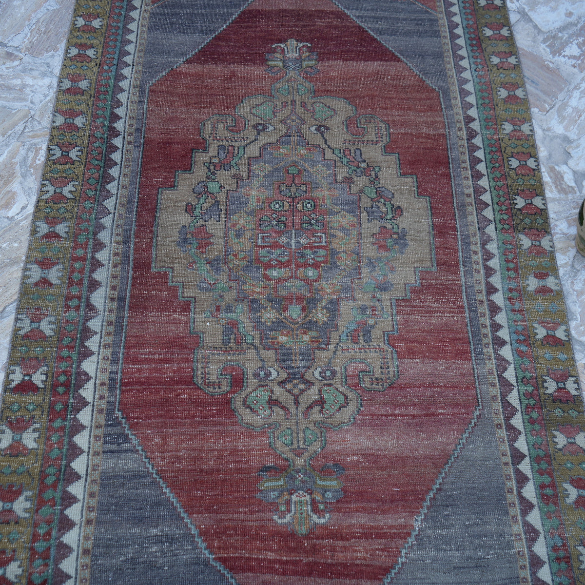 Close-up of the red vintage turkish rug showing traditional details, hand-knotted weave, wool and low pile.