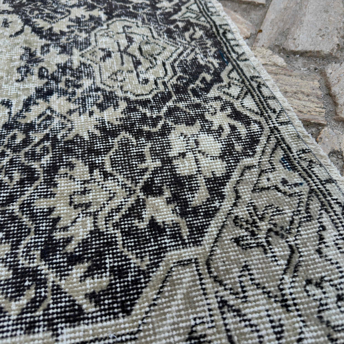 Close-up of the black vintage turkish rug showing neutral details, hand-knotted weave, wool and cotton and low pile.
