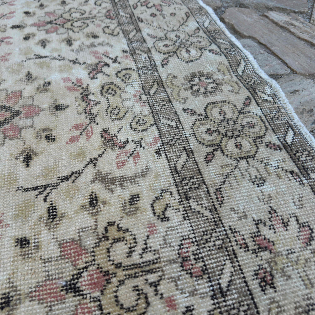 Close-up of the brown vintage turkish rug showing floral details, hand-knotted weave, wool and cotton and low pile.