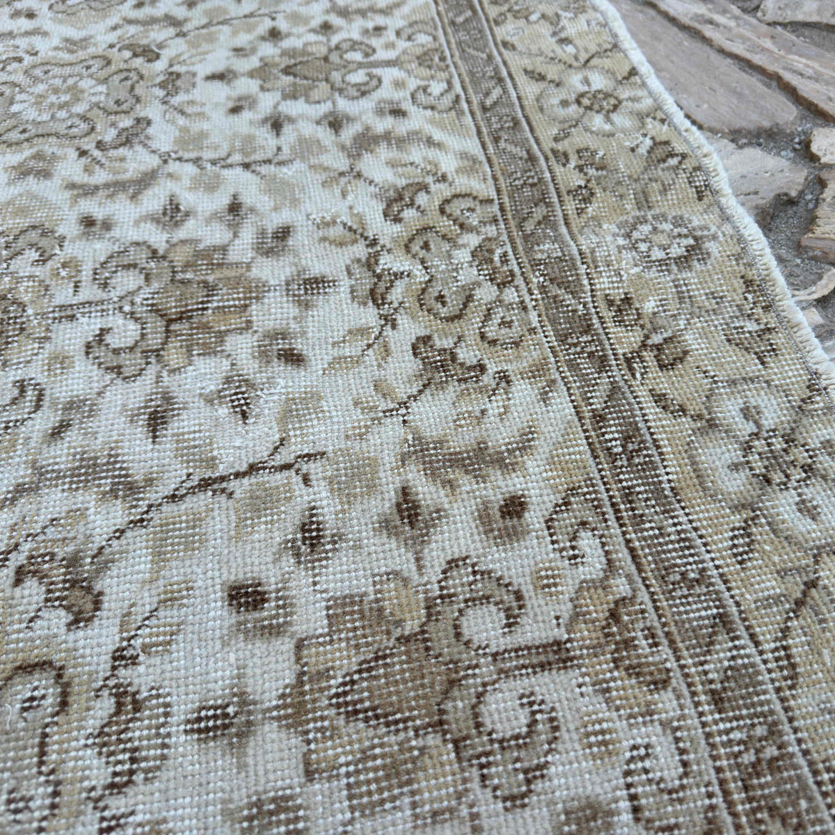 Close-up of the brown vintage turkish rug showing floral details, hand-knotted weave, wool and cotton and low pile.