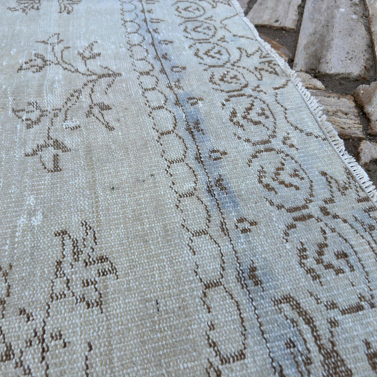 Close-up of the beige vintage turkish rug showing medallion details, hand-knotted weave, wool and cotton and low pile.
