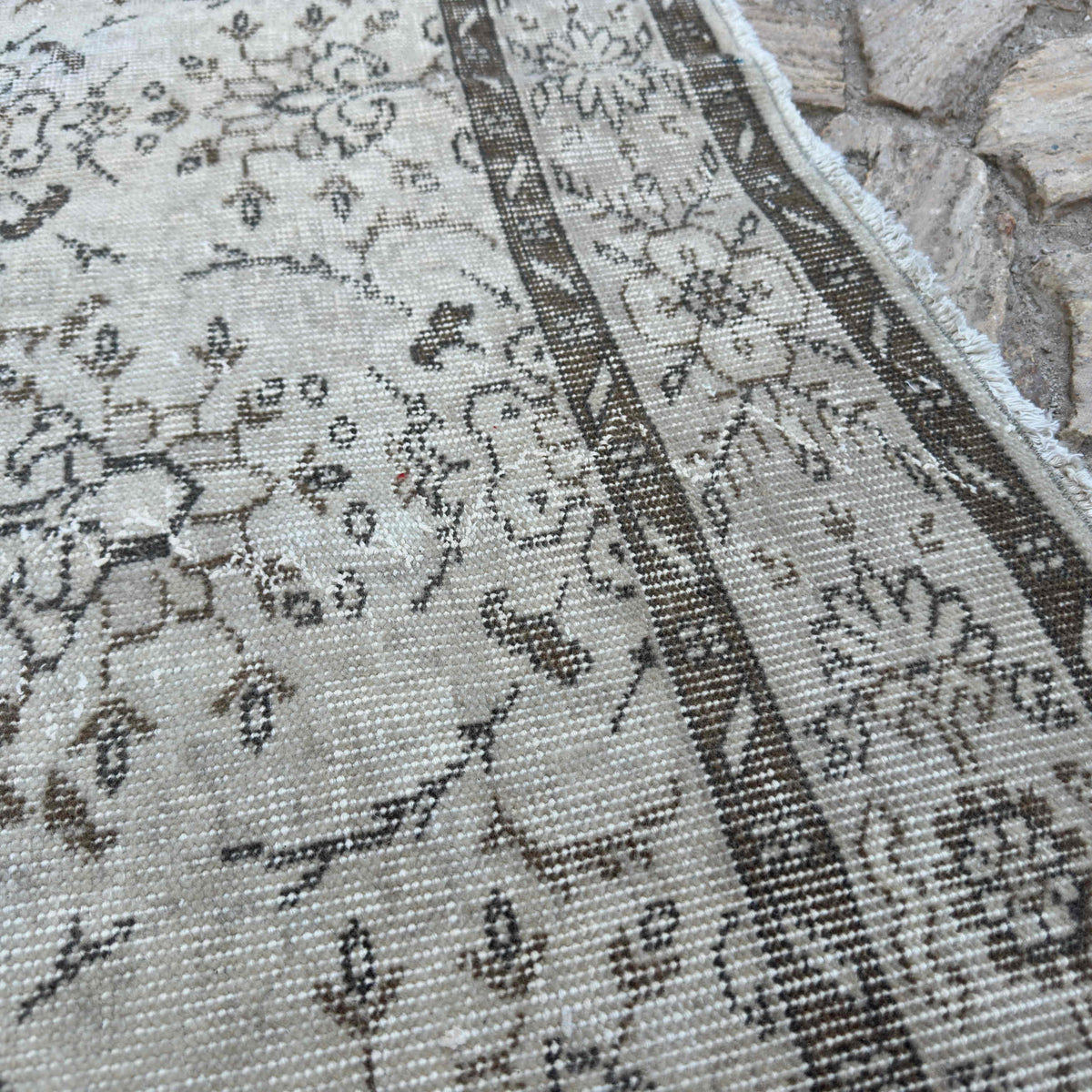 Close-up of the beige vintage turkish rug showing floral details, hand-knotted weave, wool and cotton and low pile.