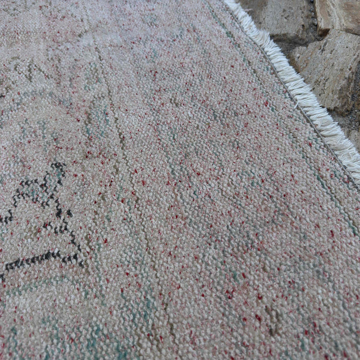 Close-up of the beige vintage turkish rug showing medallion details, hand-knotted weave, wool and cotton and low pile.