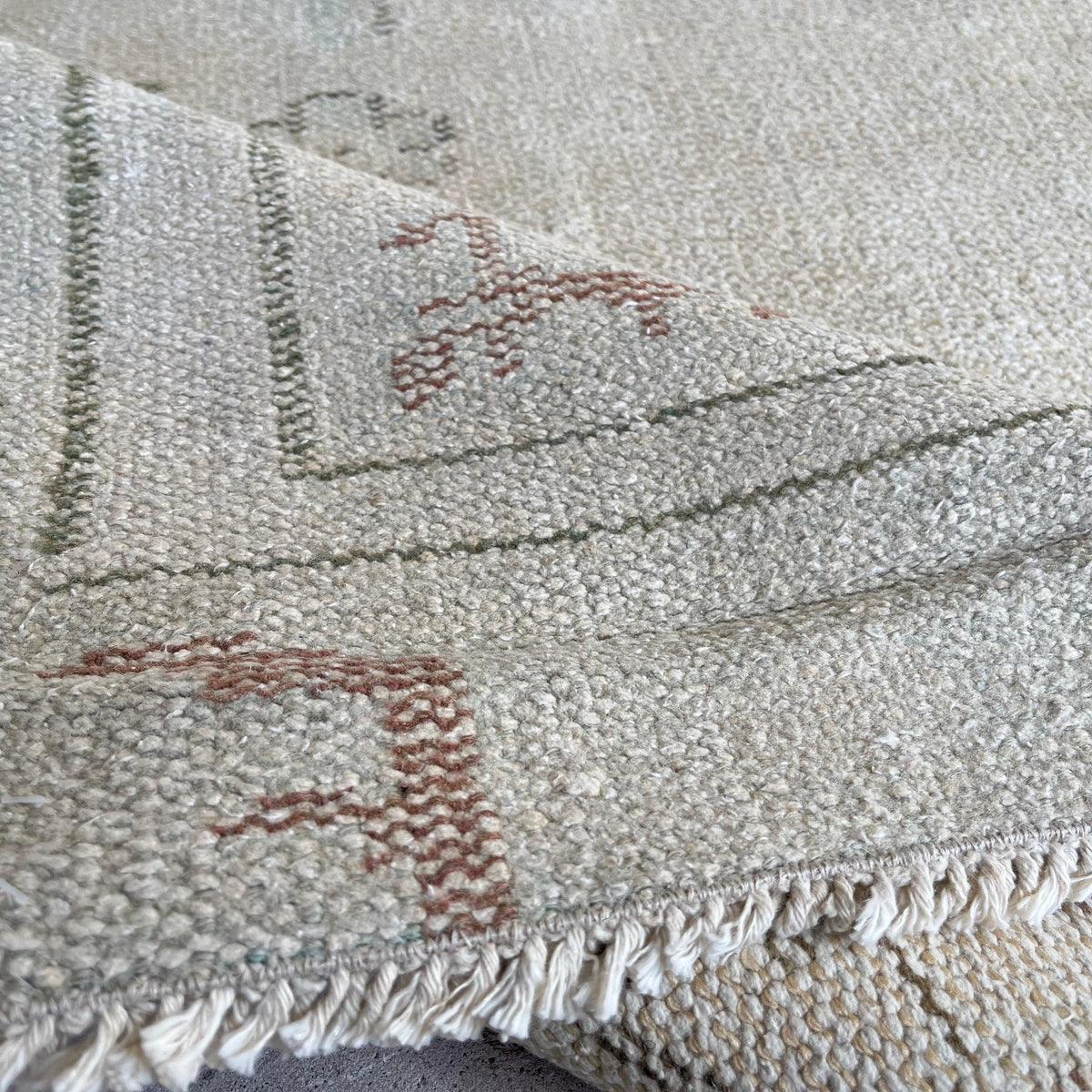 Close-up of the beige vintage turkish rug showing neutral details, hand-knotted weave, wool and cotton and low pile.