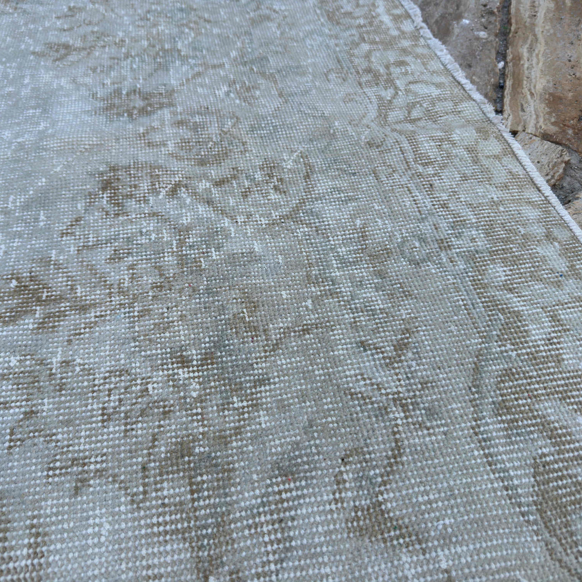 Close-up of the beige vintage turkish rug showing neutral details, hand-knotted weave, wool and cotton and low pile.