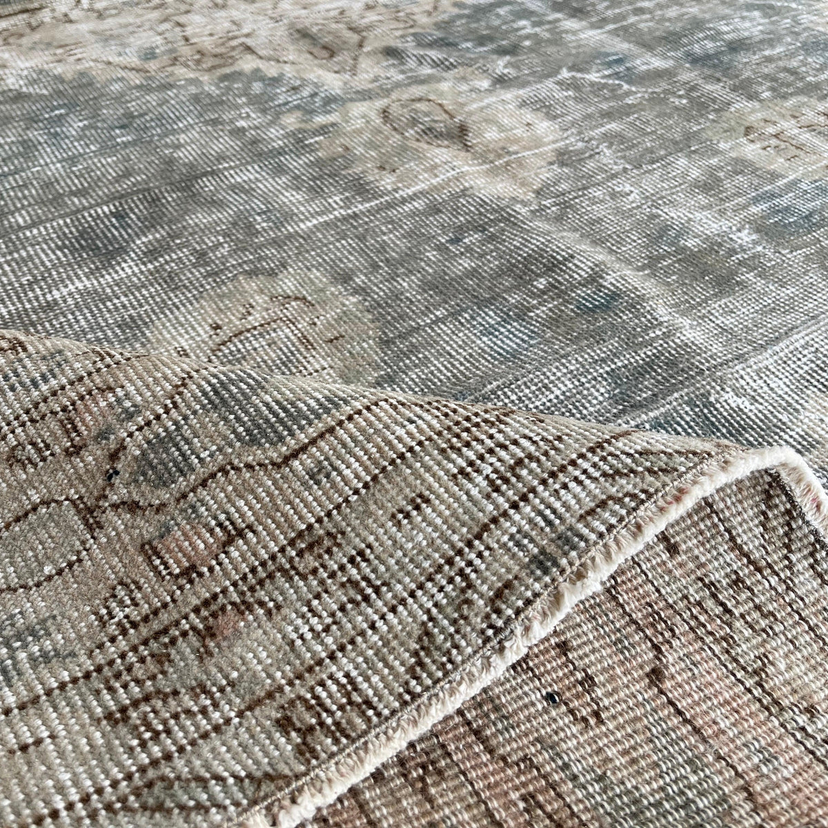 Close-up of the gray vintage turkish rug showing medallion details, hand-knotted weave, wool and cotton and low pile.