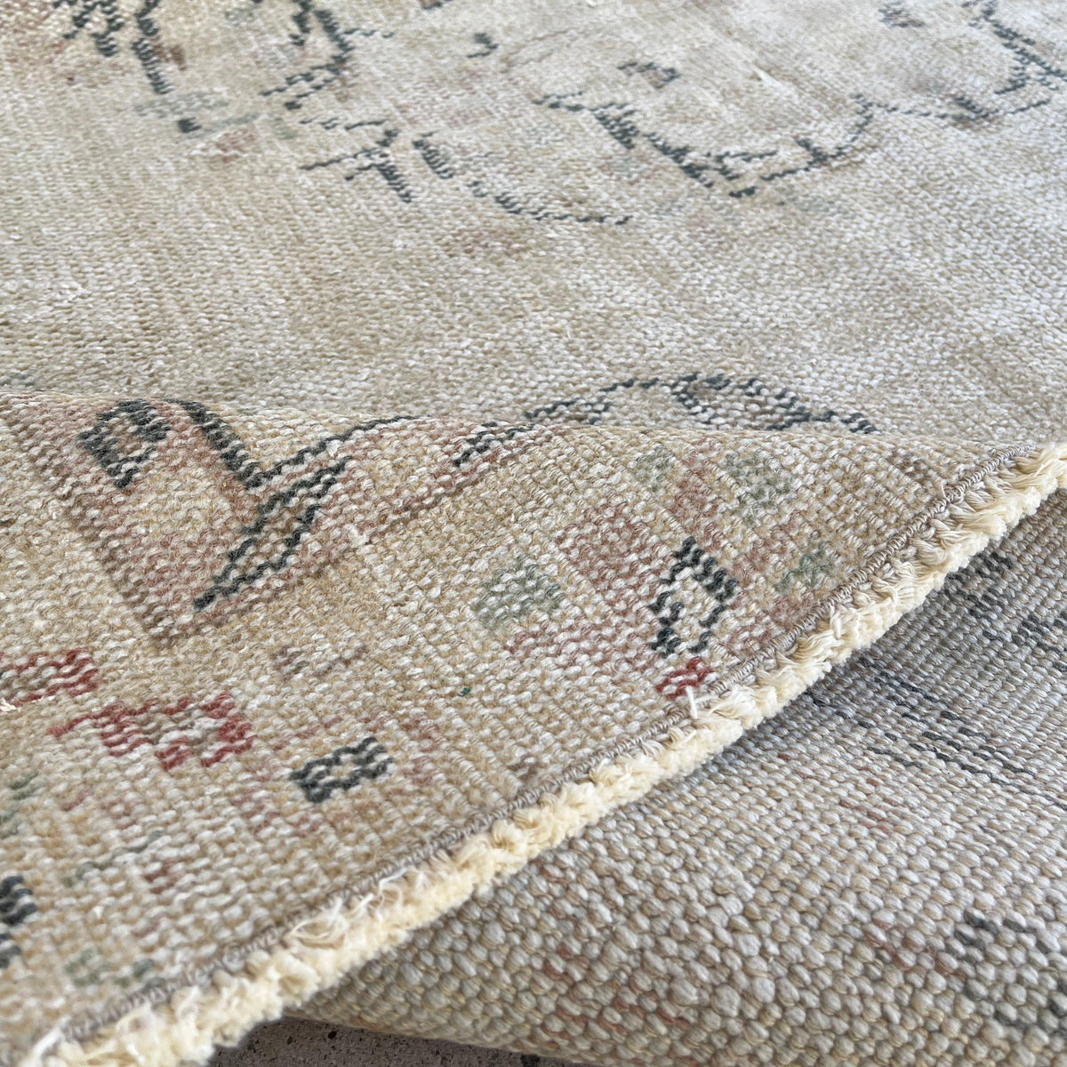 Close-up of the beige vintage turkish rug showing medallion details, hand-knotted weave, wool and cotton and low pile.