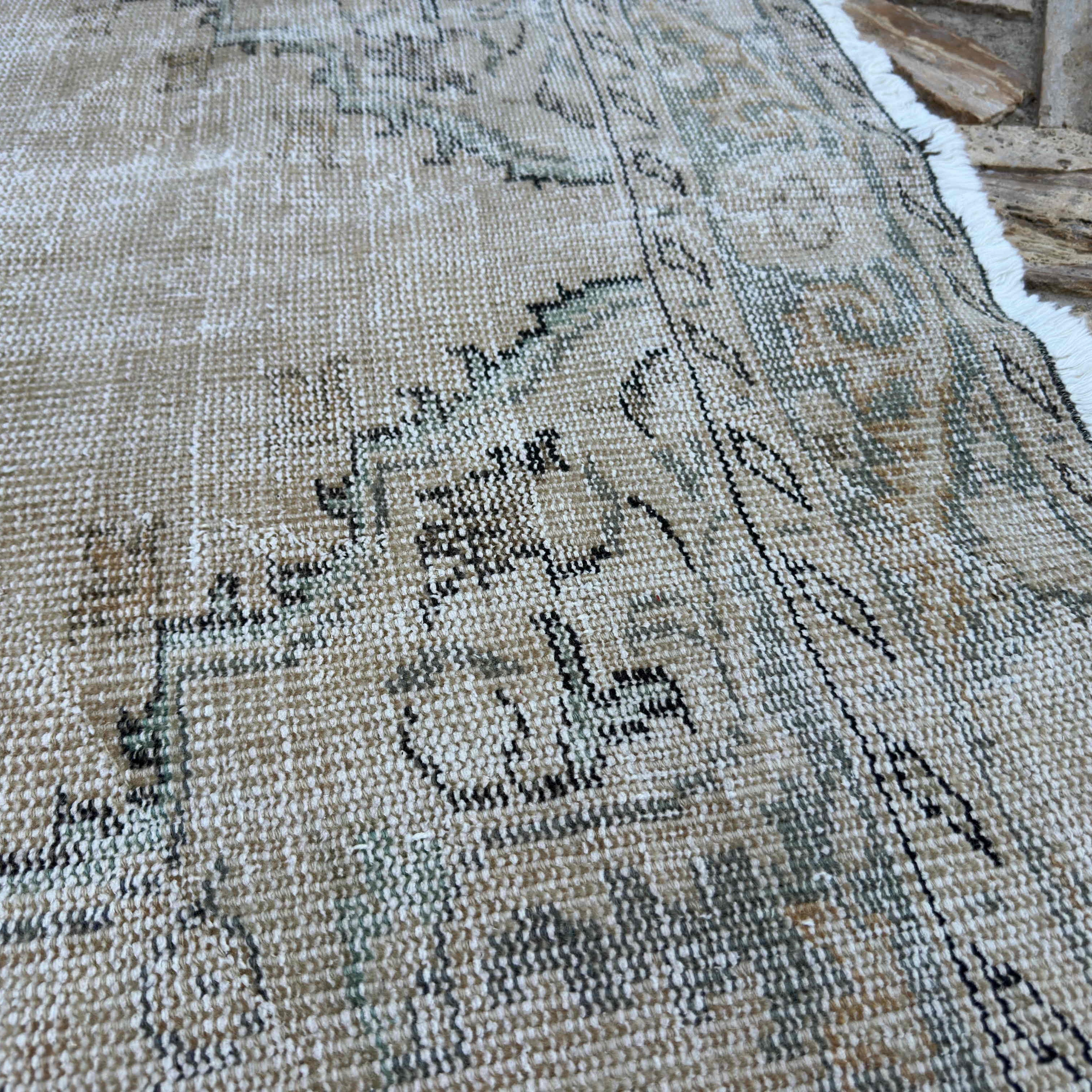 Close-up of the beige vintage turkish rug showing neutral details, hand-knotted weave, wool and cotton and low pile.