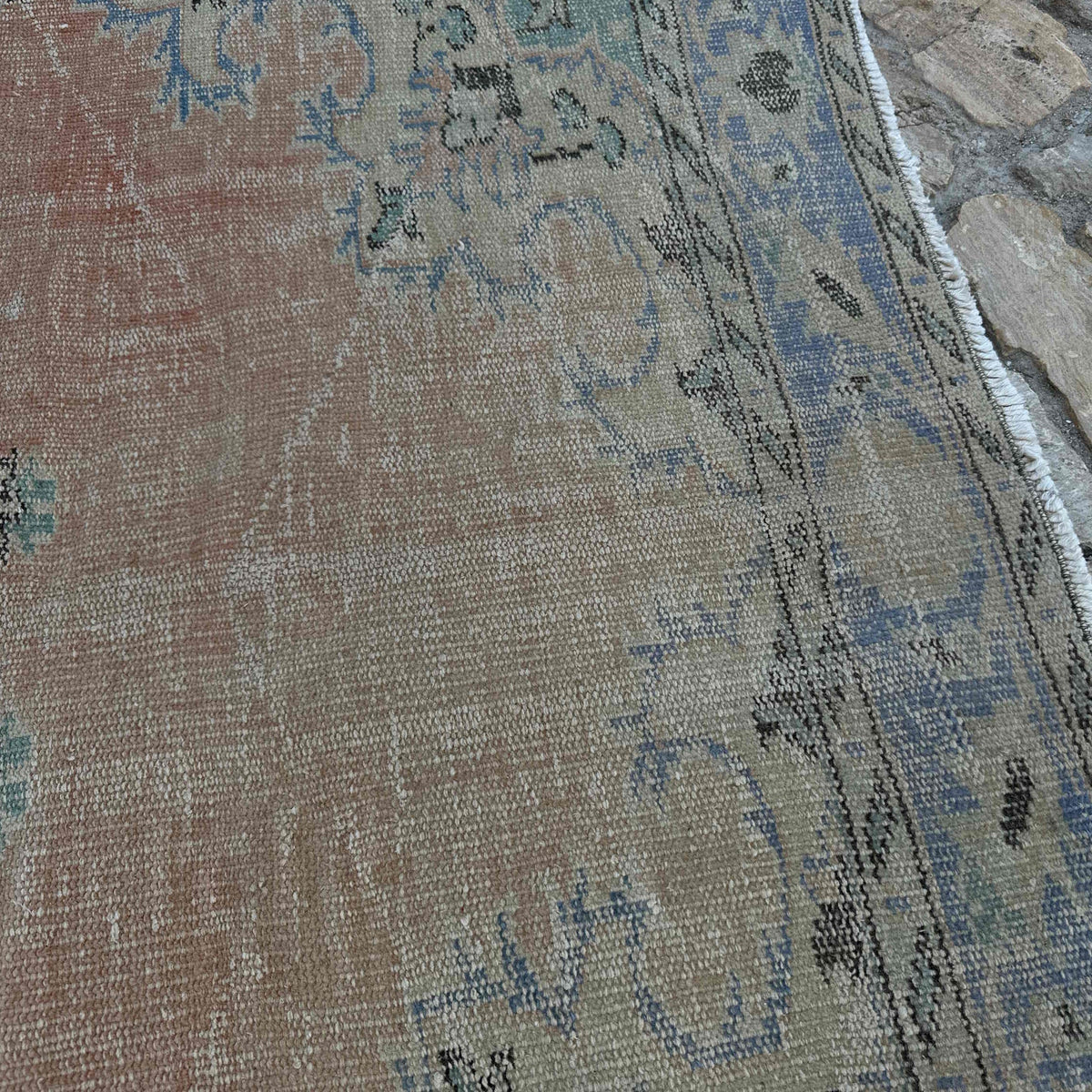 Close-up of the pale red vintage turkish rug showing medallion details, hand-knotted weave, wool and cotton and low pile.