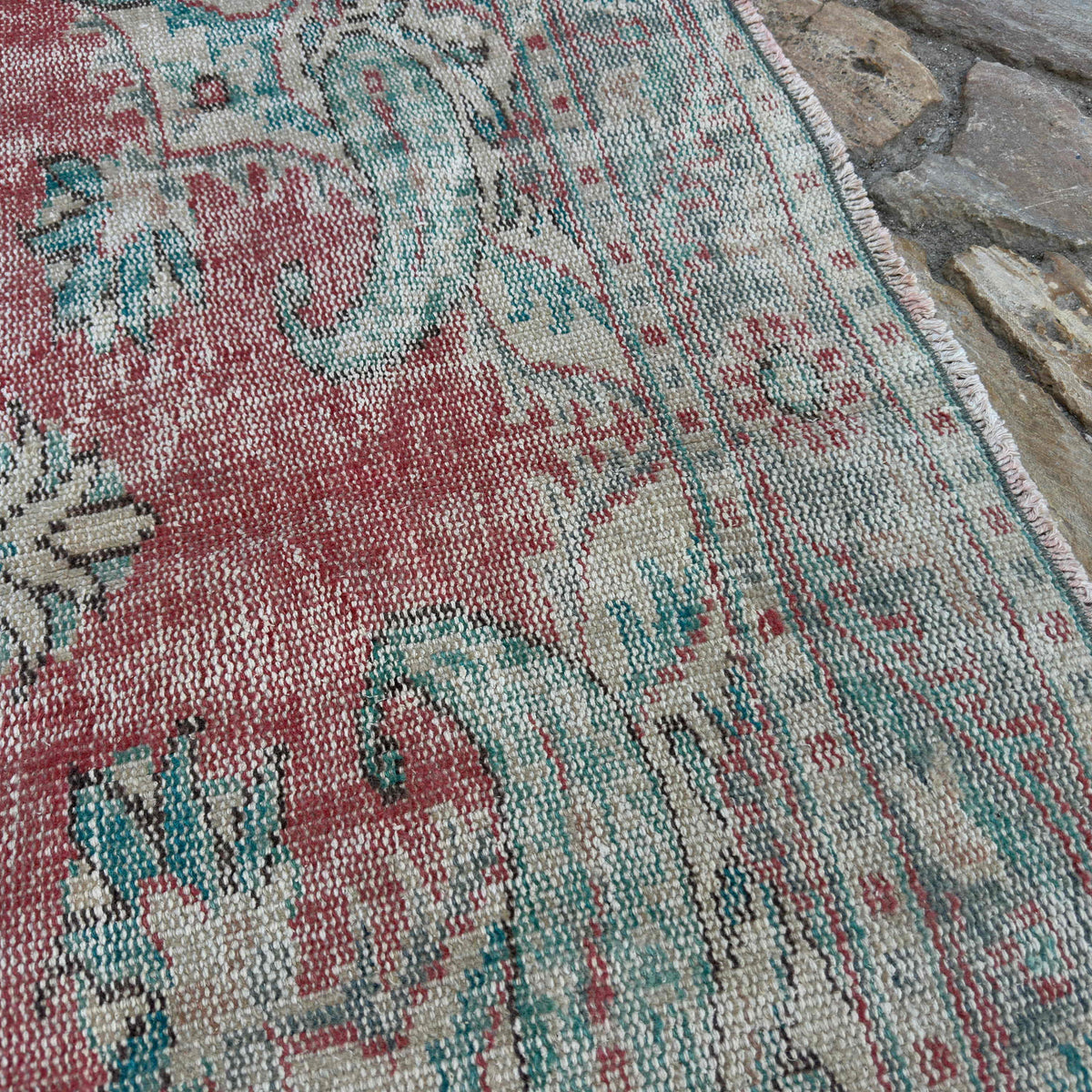 Close-up of the red vintage turkish rug showing medallion details, hand-knotted weave, wool and cotton and low pile.