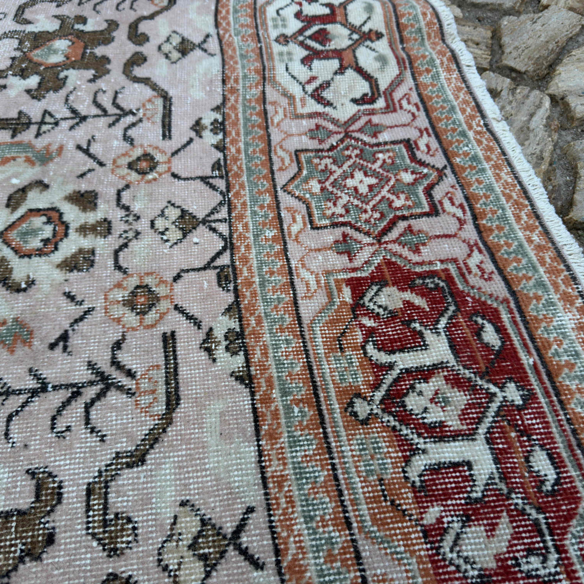Close-up of the pink vintage turkish rug showing geometric details, hand-knotted weave, wool and cotton and low pile.