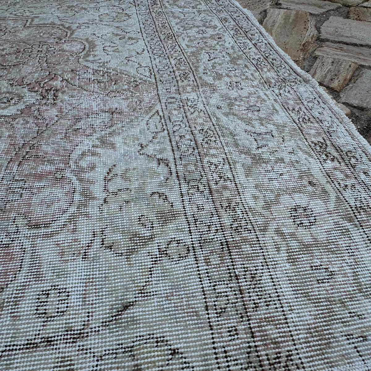 Close-up of the pale red vintage turkish rug showing neutral details, hand-knotted weave, wool and cotton and low pile.