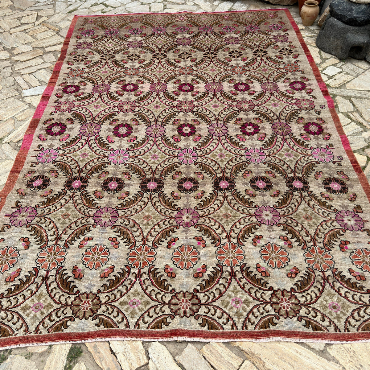 Pink 7' x 11' vintage turkish rug in wool and cotton, shown on the floor.
