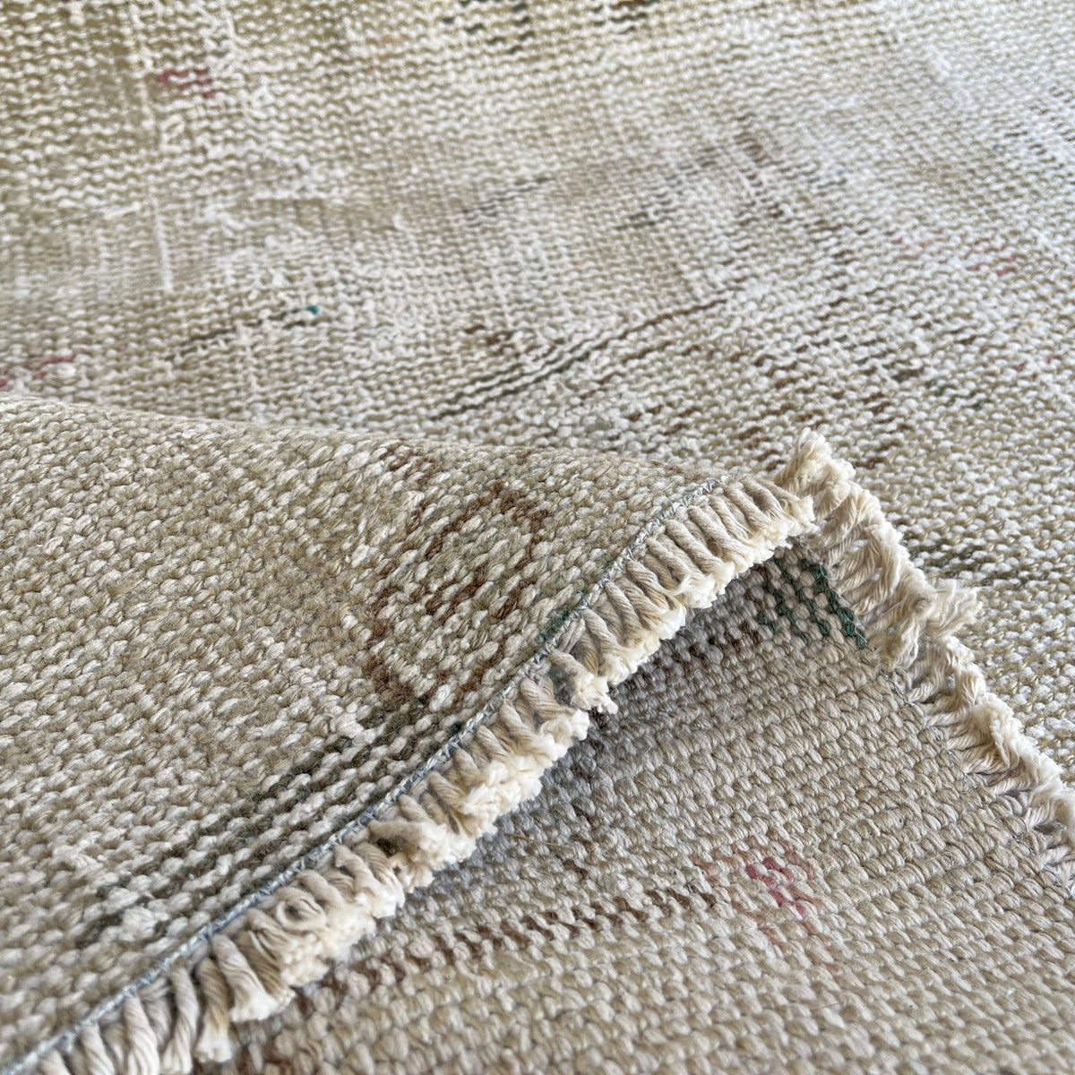 Close-up of the beige vintage turkish rug showing neutral details, hand-knotted weave, wool and cotton and low pile.