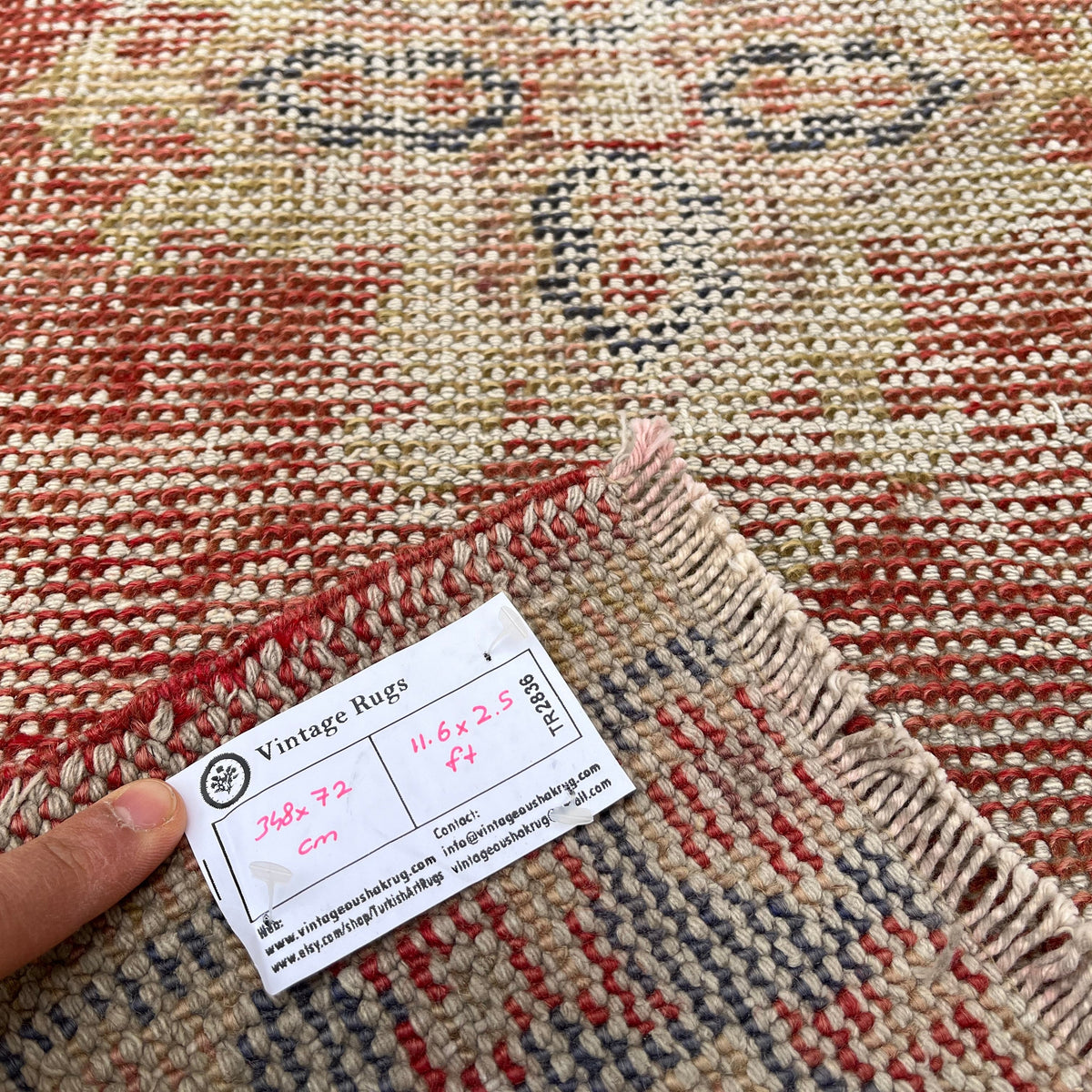 Close-up of the red vintage turkish runner rug showing geometric details, hand-knotted weave, wool and cotton and low pile.