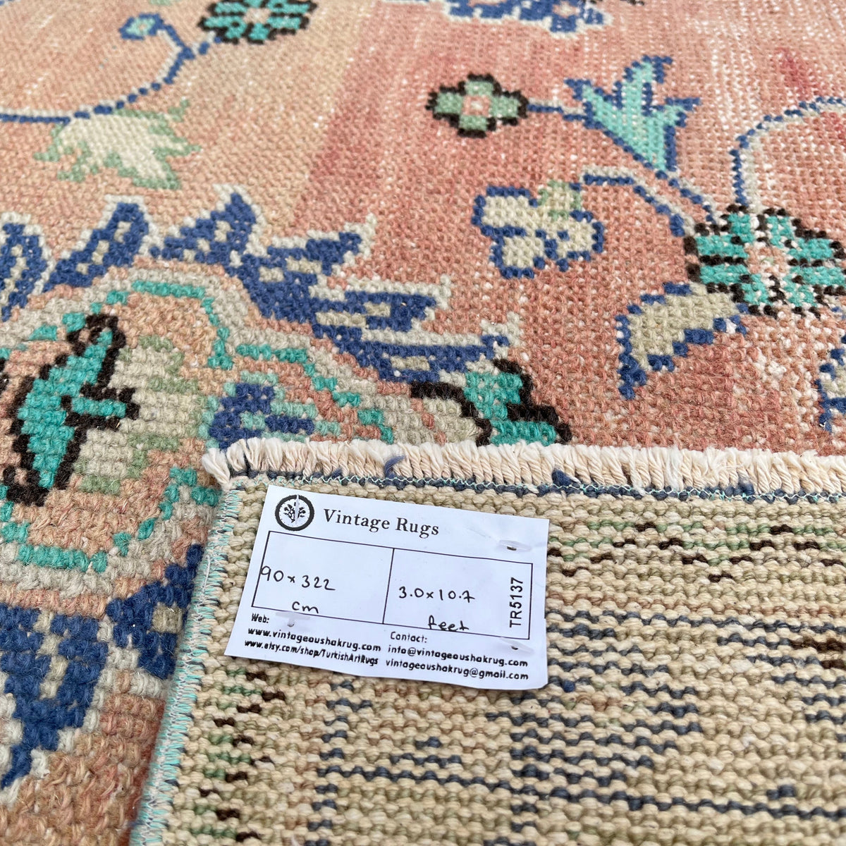 Close-up of the pale green vintage turkish runner rug showing floral details, hand-knotted weave, wool and cotton and low pile.