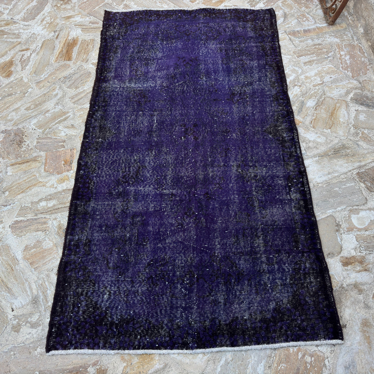 Close-up of the purple vintage Turkish wool overdyed rug showing overdyed details, hand-knotted weave, wool and cotton and low pile.