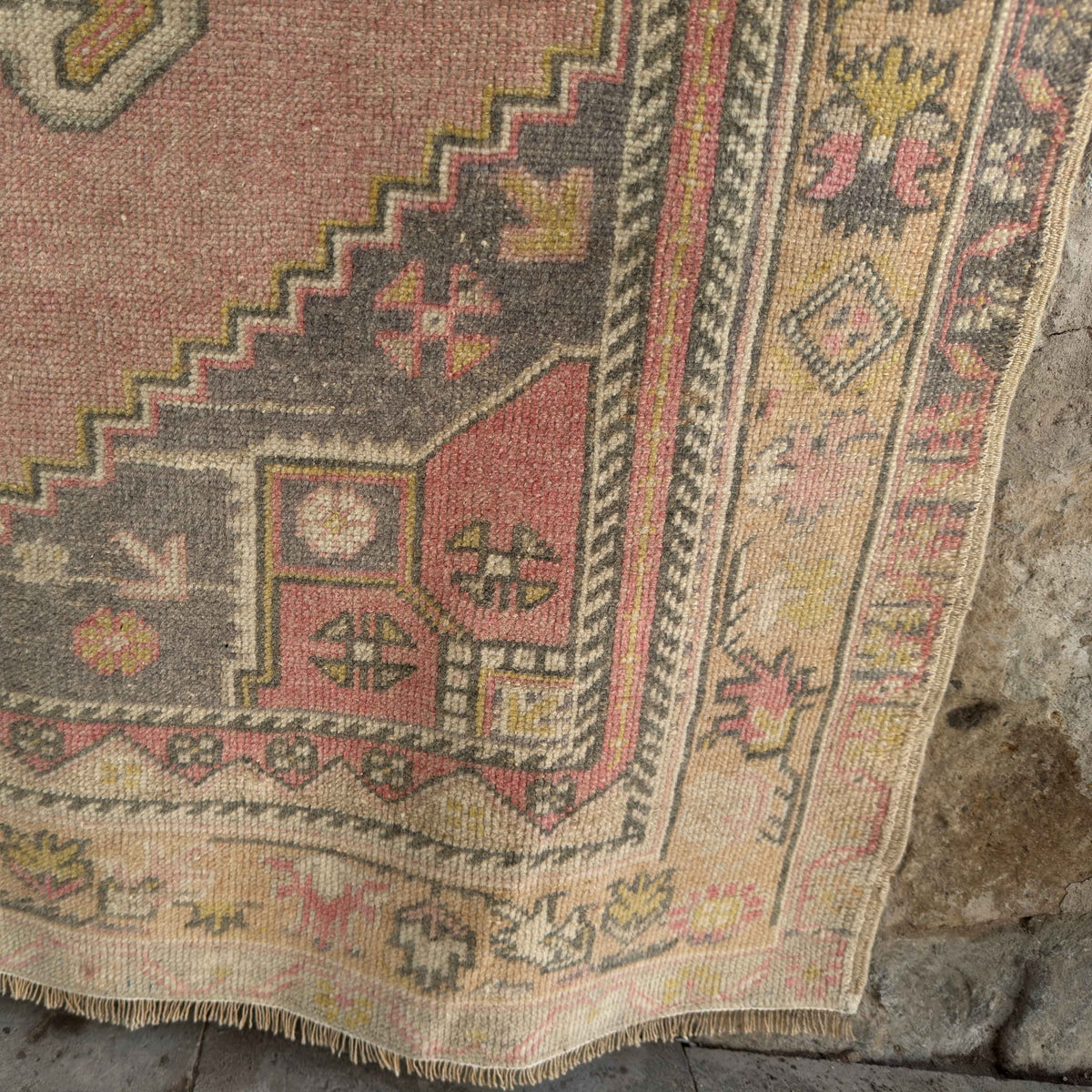 Close-up of the pink vintage Turkish wool rug showing neutral details, hand-knotted weave, wool and cotton and low pile.