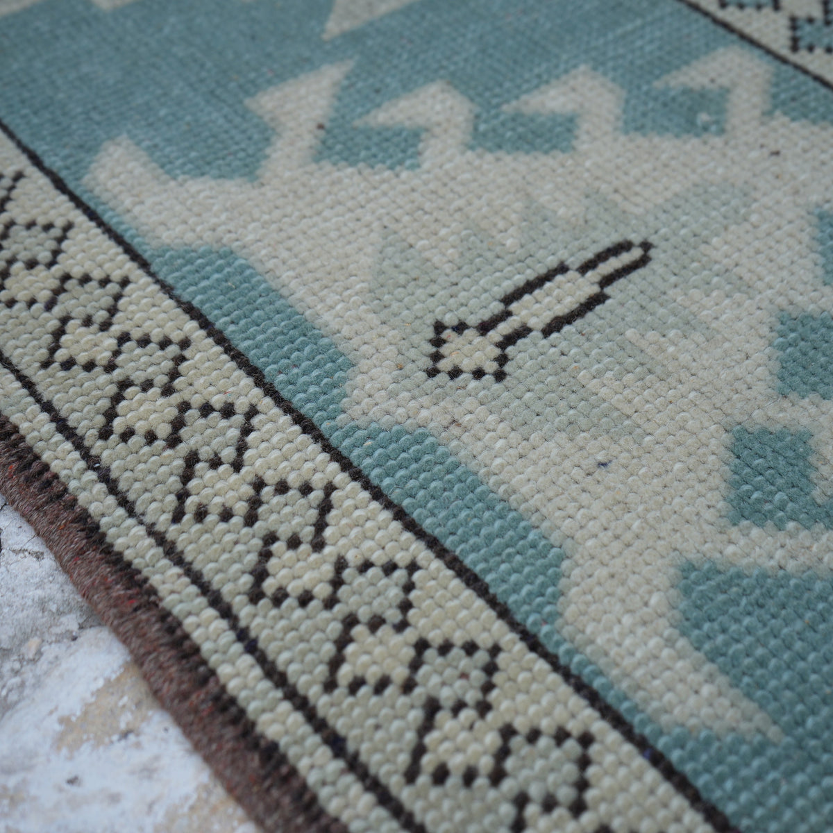 Pale Blue 7' x 10' vintage Turkish wool rug in wool, shown on the floor.