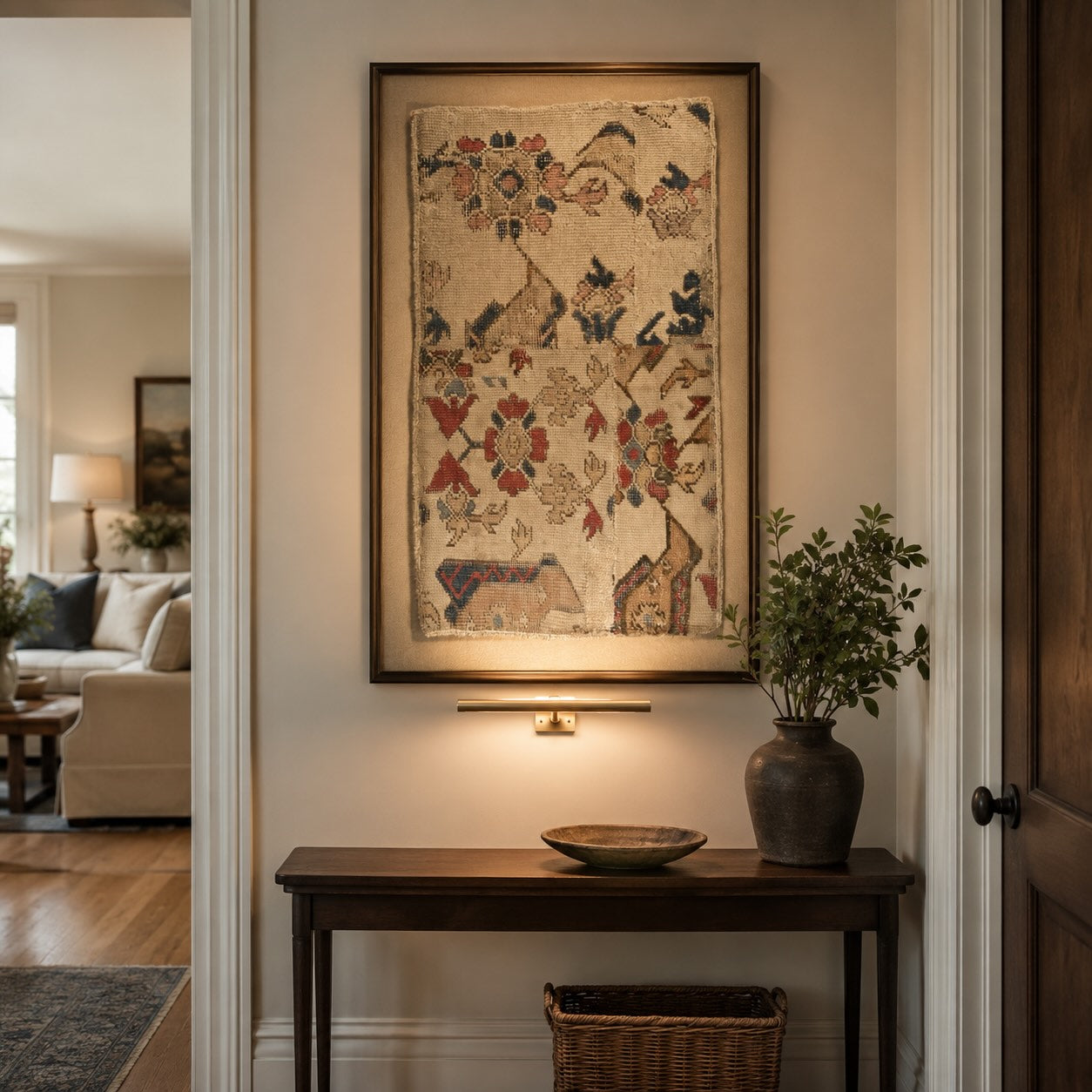 Rare antique Bird Oushak rug fragment with floral and animal motifs, framed and gallery-lit above a console table, showing how fragile hand-knotted antiques are preserved and displayed
