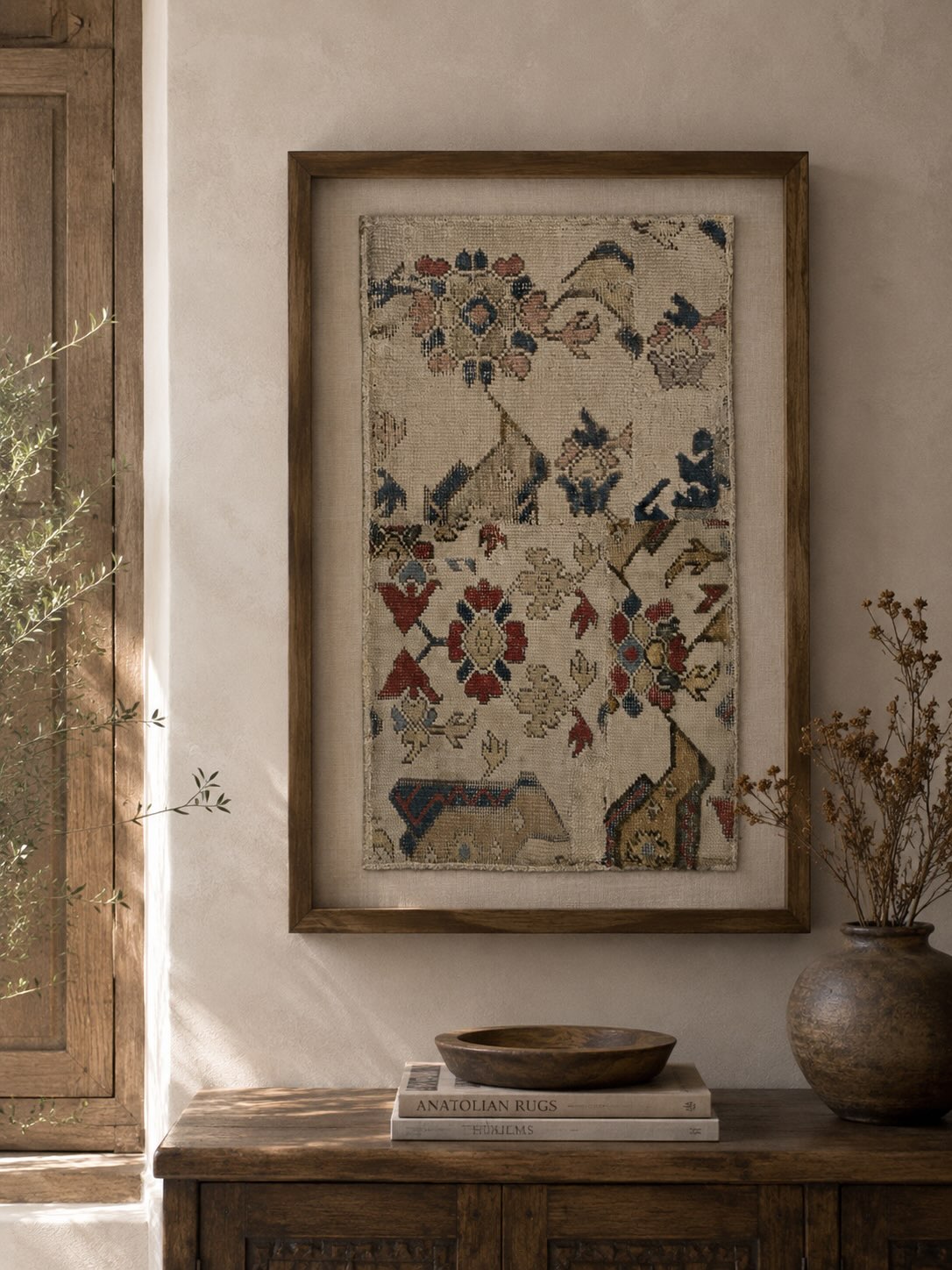 Framed antique 16th-century bird Oushak rug fragment displayed as wall art above a wooden console table