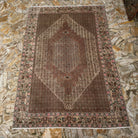 Brown 6' x 9' authentic vintage persian rug in wool and cotton, shown on the floor.