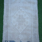 Close-up of the beige Turkish authentic vintage rug showing neutral details, hand-knotted weave, wool and low pile.