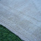 Beige 2' x 4' Turkish authentic vintage rug in wool, shown on the floor.