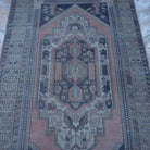 Close-up of the pink Turkish authentic vintage rug showing traditional details, hand-knotted weave, wool and low pile.