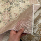 Close-up of the beige Turkish authentic vintage rug showing floral details, hand-knotted weave, wool and cotton and low pile.