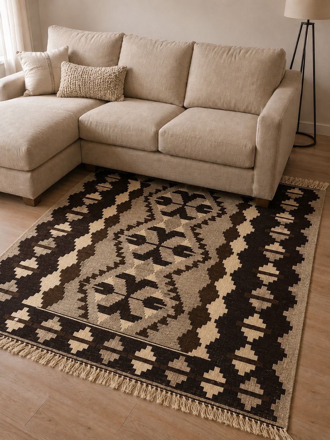 Isaias vintage black and brown kilim rug placed under a beige sectional sofa, illustrating a bold contrast rug color pairing for a beige couch.