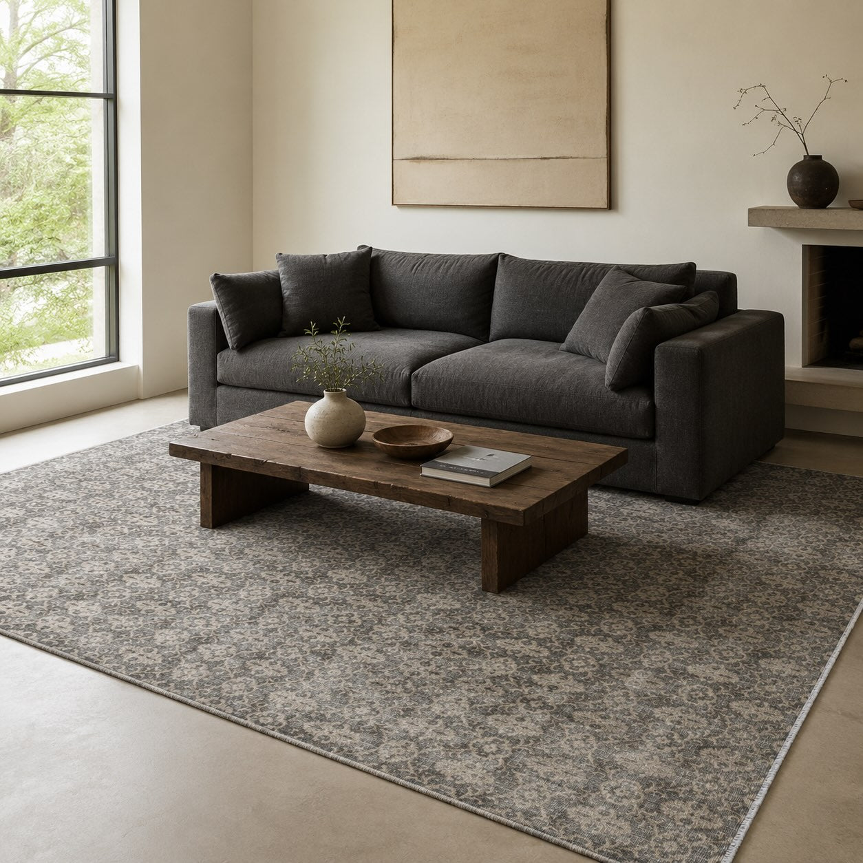 Gray and cream floral-pattern vintage rug beneath a charcoal sofa and wood coffee table in a minimalist living room