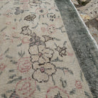 Close-up of the pale green Turkish distressed floral rug showing floral details, hand-knotted weave, wool and cotton and low pile.