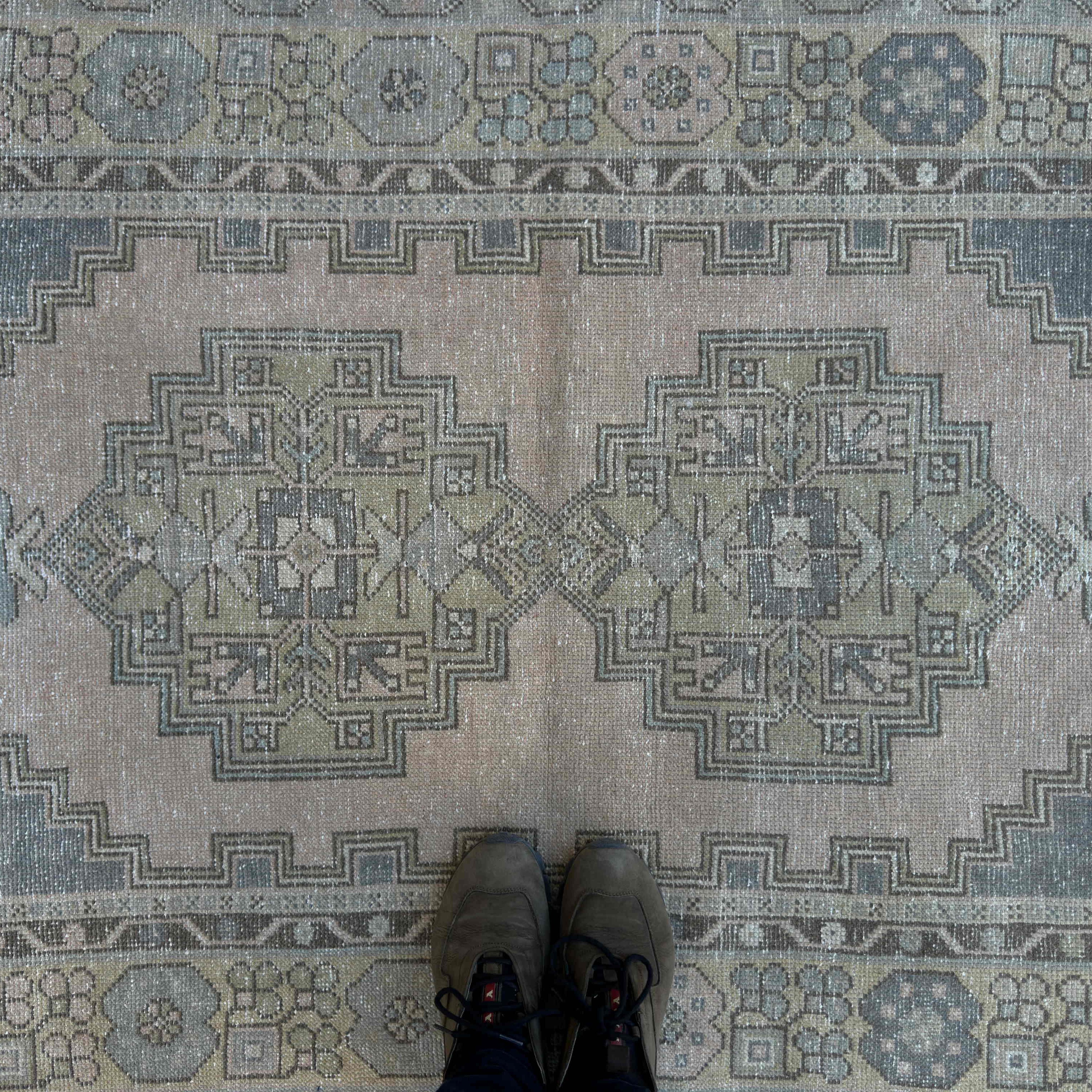 1970s beige Turkish distressed rug with traditional design, hand-knotted weave and low pile.